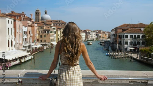a beautiful girl in a sundress stands on a bridge in a European city