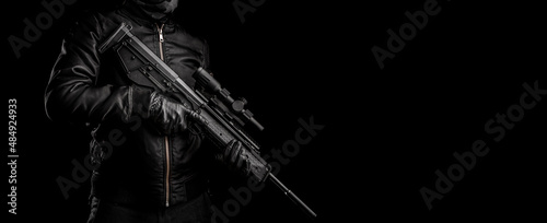 Photography A man in dark clothes holds an automatic carbine in his hands