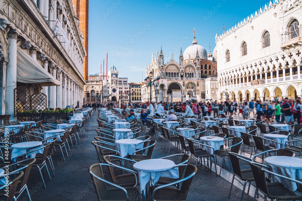 Ancient square of San Marco located in historic center of venice with ancient cathedral basilicas and architecture buildings for visiting during summer travel vacations, table of street cafe for rest