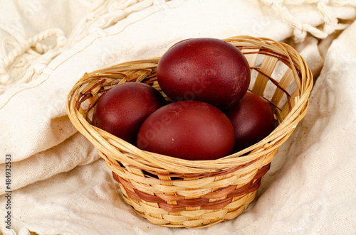 Wicker bowl with red hand-painted easter eggs. Studio Photo