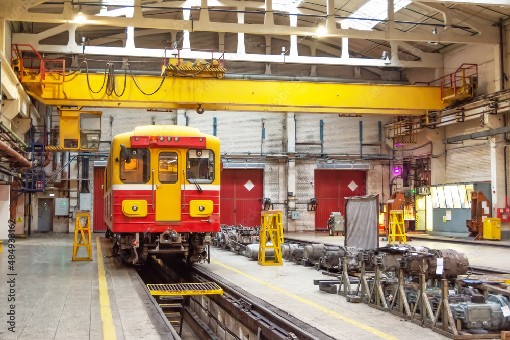Obraz premium Subway passenger car locomotive, electric transport in the depot on suspended jacks for service. Wheelsets engine nearby.