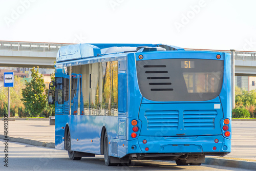 City bus in blue at the bus stop before departure, rear view.