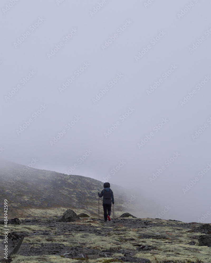 A young girl in the mountains goes into the clouds. dense clouds