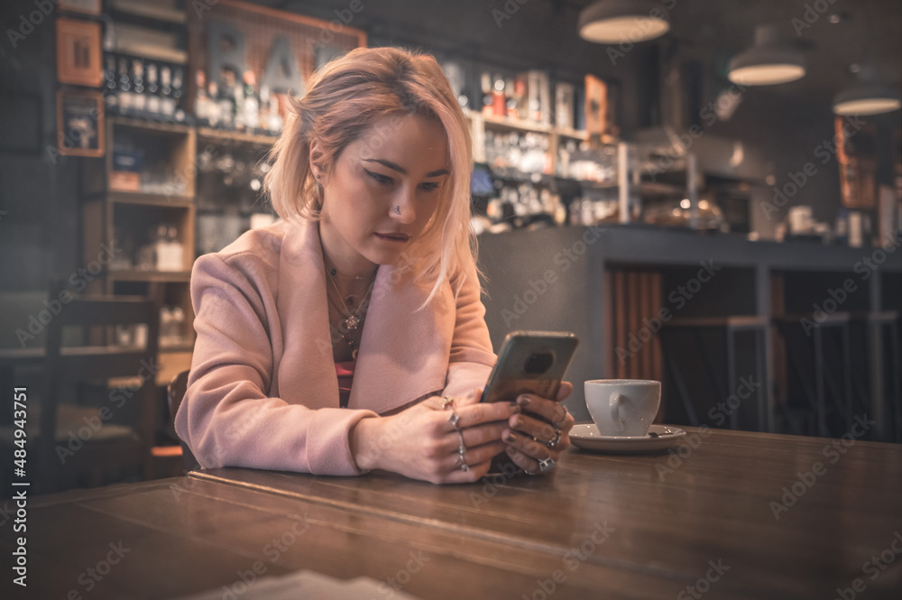 Young woman using smartphone in cafe with dark lighting Young woman using smartphone in cafe with dark lighting