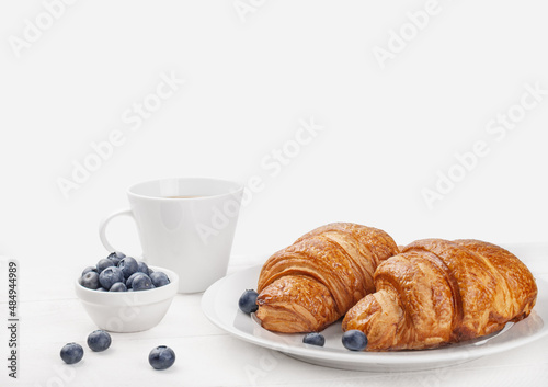 blueberry croissants and black tea on white wooden background