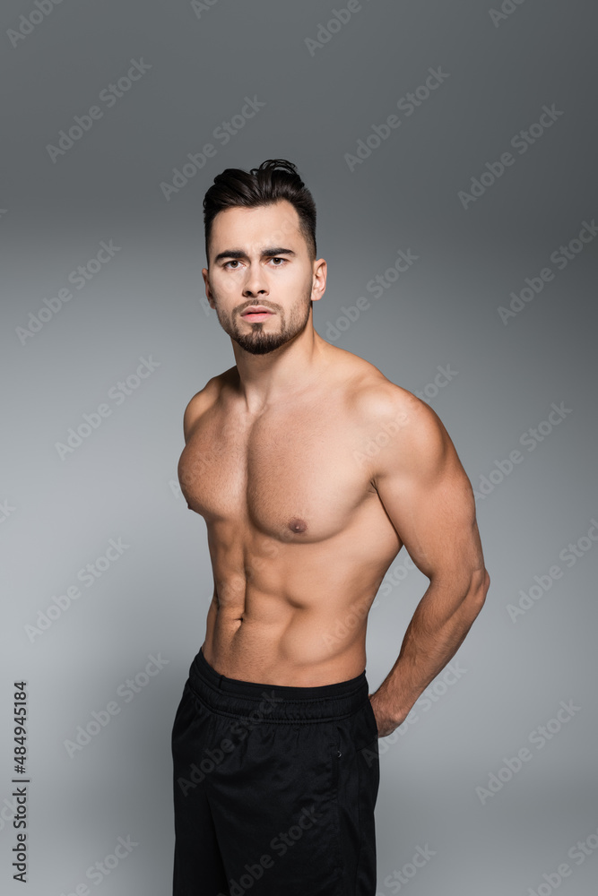 young muscular sportsman standing isolated on grey. young muscular sportsman standing isolated on grey.