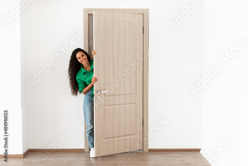 Cheerful lady looking out of door standing in doorway