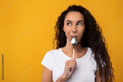 Fototapete Excited Smiling Latin Lady Holding Spoon In Mouth