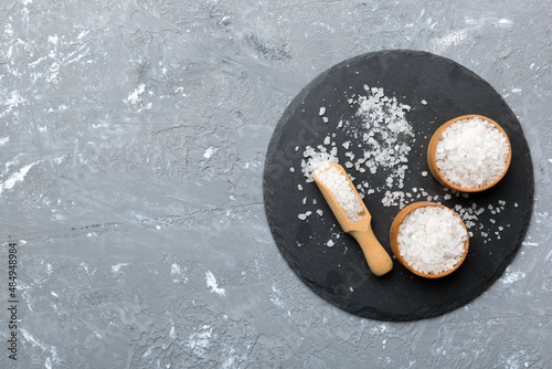 A wooden bowl of salt crystals on a wooden background. Salt in rustic bowls, top view with copy space photo