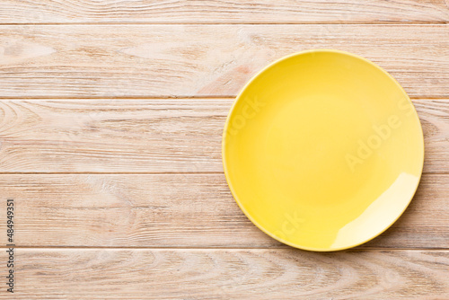 Top view of empty yellow plate on wooden background. Empty space for your design