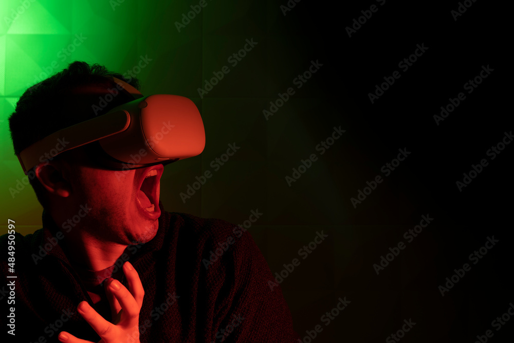 Man in white virtual reality goggles screaming in fear in red light Man in white virtual reality goggles screaming in fear in red light