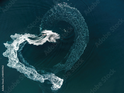 Aerial view on heart-shaped trace on turquoise sea from a jet ski. Valentine day love symbol of heart shape, love, feelings. Water splash love heart shape. Romantic couple trip on Valentine's Day.