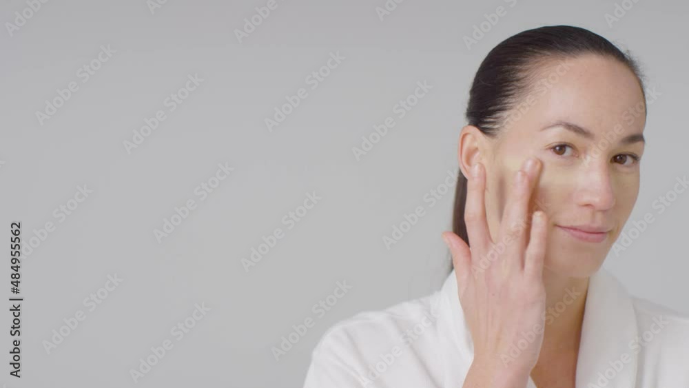 Mid Shot of Young Woman applying Concealer with Finger with Copy Space.