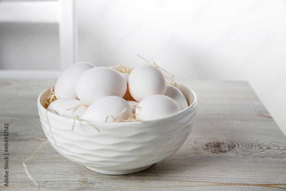 Patterned bowl with eggs on beige wooden table in white scandinavian style kitchen. Place for text. Copy space Patterned bowl with eggs on beige wooden table in white scandinavian style kitchen. Place for text. Copy space