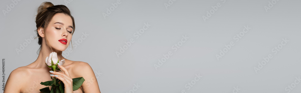 charming woman with red lips and closed eyes holding white rose isolated on grey, banner.