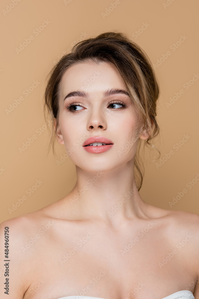 young and pretty woman with bare shoulders looking away isolated on beige. young and pretty woman with bare shoulders looking away isolated on beige.