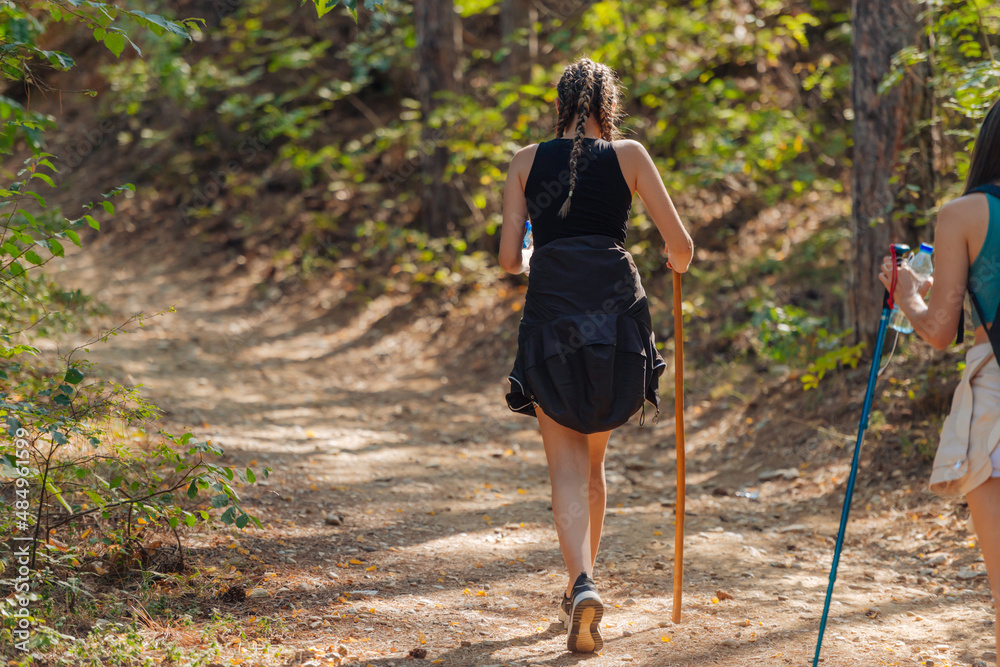 Sisters hiking through beautiful woods while wearing a backpack and enjoying nature. Female bonding. Sisters hiking through beautiful woods while wearing a backpack and enjoying nature. Female bonding.