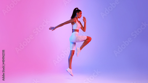 Fototapeta Naklejka Na Ścianę i Meble -  Woman Doing Elbow-To-Knee Crunch Standing Over Pink And Blue Background