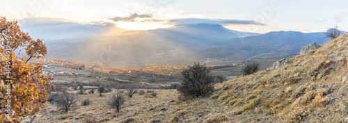 Autumn view of the valley under the mountain illuminated by the sun