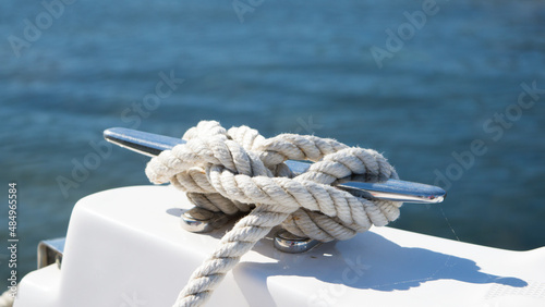 Tight knot on a steel cleat of a boat, detail of tied nautical rope