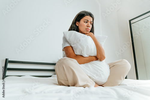 Young woman sitting on the bed looking sad