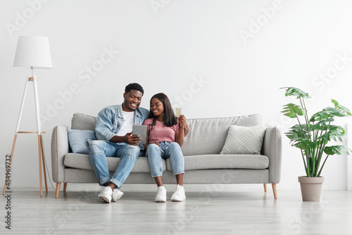 Black couple using pc and debit credit card at home