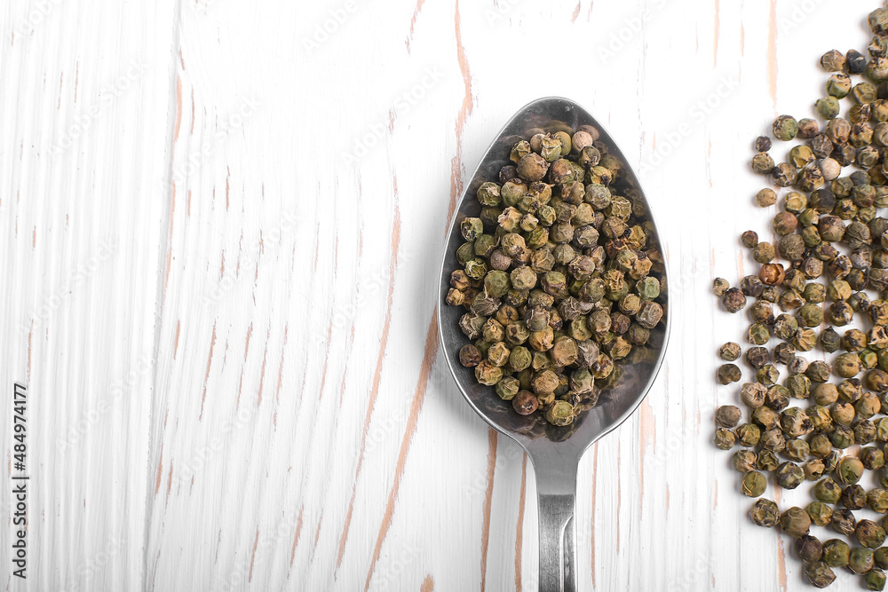 dried green pepper in a spoon on a white wooden background dried green pepper in a spoon on a white wooden background