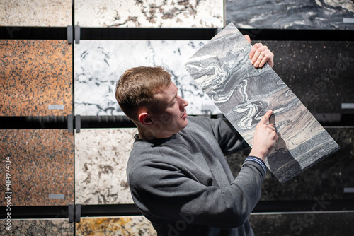 a man in the granite tile department shows one piece of granite he has chosen
