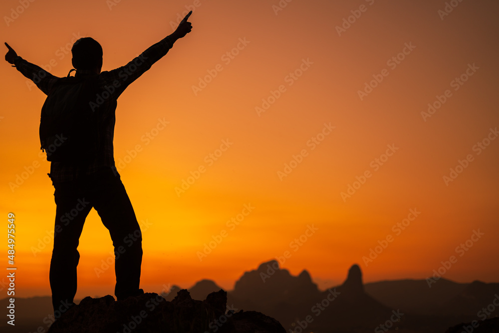 Silhouette of success man hiker outstretched arms on top of the mountain with beautiful sunset.Concept of adventure travel