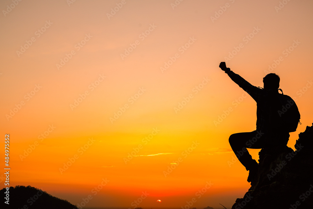 Silhouette of success man hiker outstretched arms on top of the mountain with beautiful sunset.Concept of adventure travel