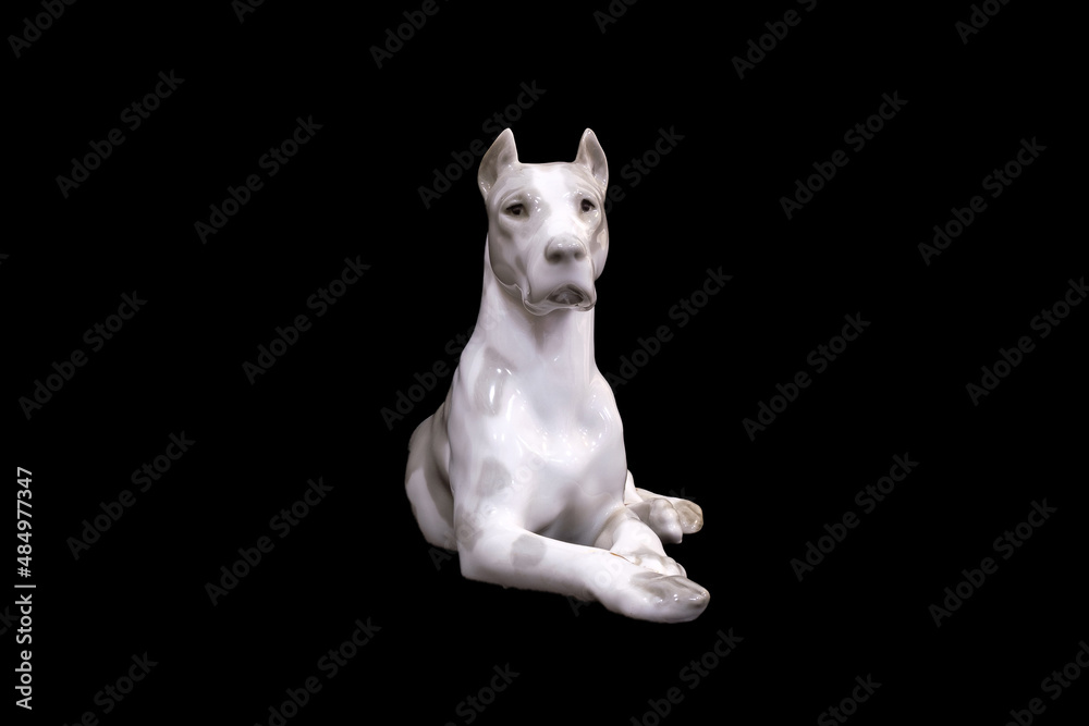 a dog of the White Great Dane breed is isolated on a black background. porcelain figurine - obrazy, fototapety, plakaty 