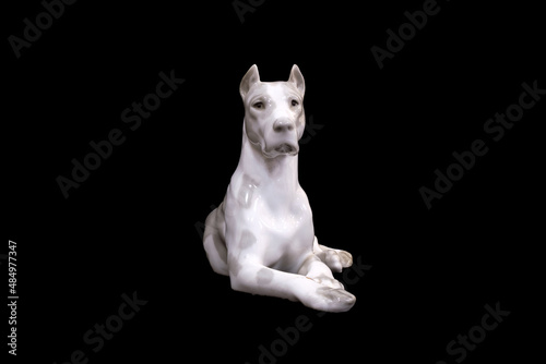 a dog of the White Great Dane breed is isolated on a black background. porcelain figurine