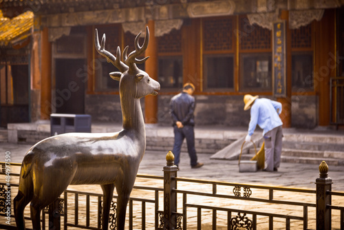 Two workers and a deer statue in The enchanting Forbidden City in Beijing in the morning sunlight. Beijing, China