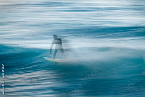 Blurred silhouette of a surfer on a wave. Concept of movement and speed