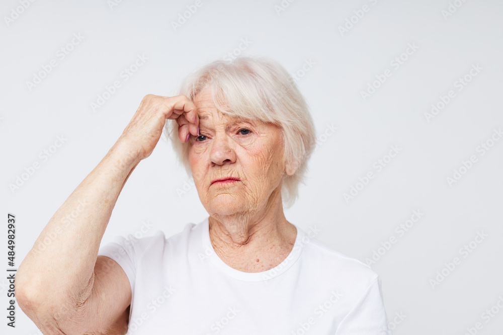 Photo of retired old lady holding his head discontent problem light background Photo of retired old lady holding his head discontent problem light background