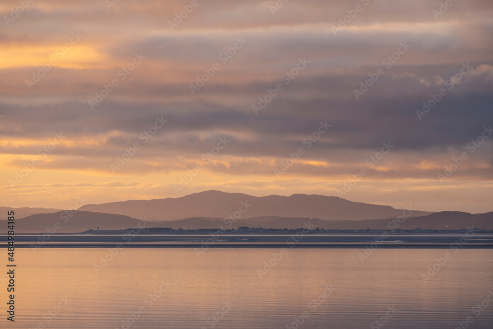 Beautiful sunset landscape image of Solway Firth viewed from Silloth during stunning Autumn sunset with dramatic sky and cloud formations