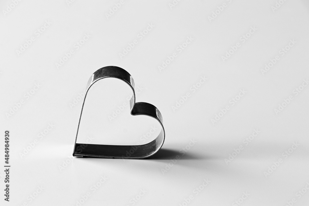 Heart of metal on a white table. Cutter, gingerbread. Loneliness, emptiness, love, romance, marriage, engagement, infatuation, loss of love, illness, grief, partnership. Outline, shape, contrast. Heart of metal on a white table. Cutter, gingerbread. Loneliness, emptiness, love, romance, marriage, engagement, infatuation, loss of love, illness, grief, partnership. Outline, shape, contrast.