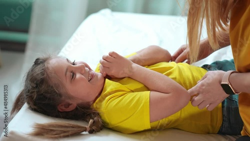 mother tickle daughter. happy family a playing on the bed at home. happy family home kid dream concept. mom tickles daughter play lifestyle laugh fun. mom tickle daughter lying on the bed
