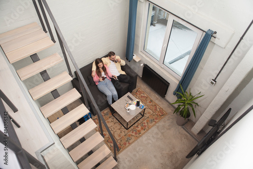 Top view shot of a couple hugging, watching tv at their hotel room while travelling together