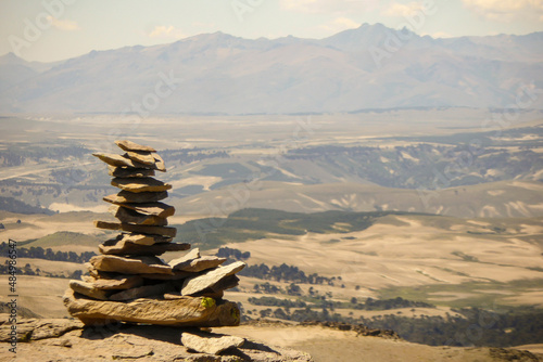 Plain stones stacked called apacheta with some moutains at the background in light colours in Villa Pehuenia, Neuquén, Argentina.  © Sebastian