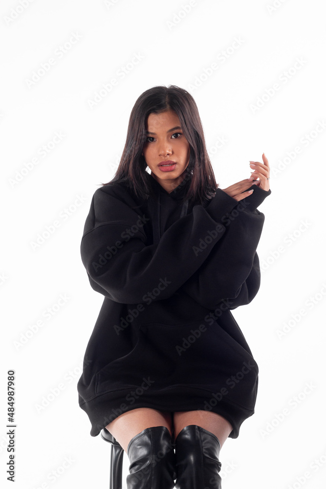 Attractive woman of Latin appearance wears a dark hoodie on a white isolated background. The girl looks sexy and happy. The elegant brunette is wearing a black sweatshirt. All-season clothing Attractive woman of Latin appearance wears a dark hoodie on a white isolated background. The girl looks sexy and happy. The elegant brunette is wearing a black sweatshirt. All-season clothing