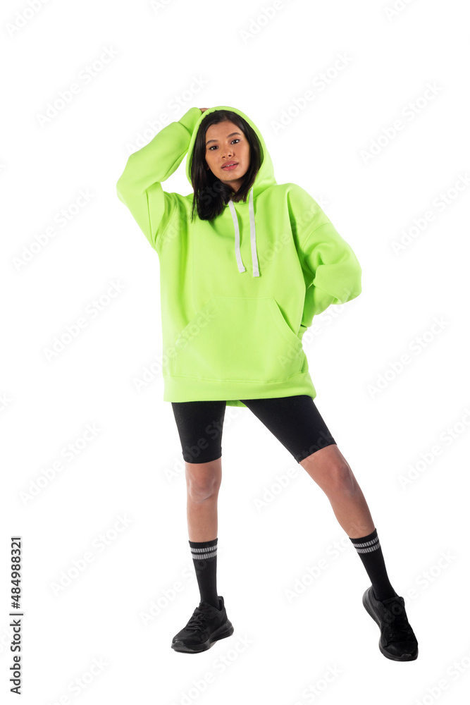 Attractive woman of Latin appearance wears a green hooded hoodie on a white background. The girl looks sexy and happy. The elegant brunette is wearing a dark sweatshirt. All-season clothing