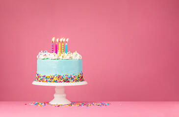 Blue Birthday Cake with Five Candles over Pink Background