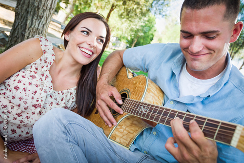 Young Adult Man Playing Guitar for His Girlfriend in the Park. © Andy Dean