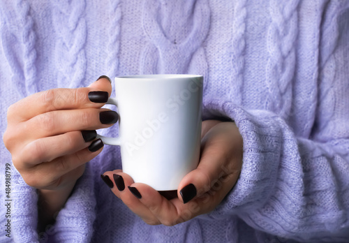 Woman in violet knitted sweater holding cup