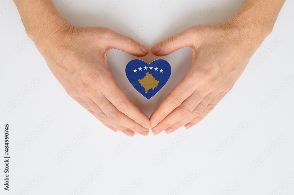 Obraz premium The national flag of Kosovo in female hands. The concept of patriotism, respect and solidarity with the citizens of Kosovo.