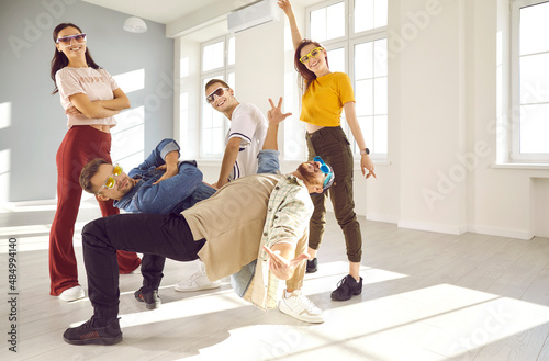 Group of people dancing modern dances. Team of cheerful young dancers have fun while performing hip-hop or breakdancing in studio. Portrait of street style dancers. Entertainment and hobby concept.