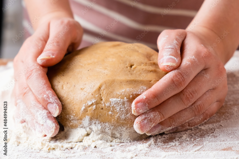 Top view of woman hands kneading the dough for buns, pie, cookies or pastry on the wooden desk. Process of homemade cooking.