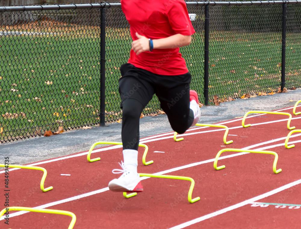 Runner running over yellow mini hurdles at track practice