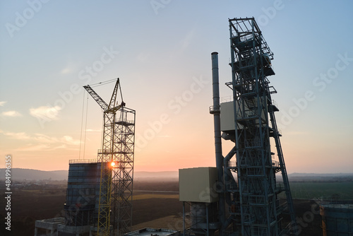 Aerial view of cement factory with high steel plant structure and tower crane at industrial production area. Manufacture and global industry concept